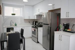 a kitchen with white cabinets and a stainless steel refrigerator at New Suite 15min from DT Van & Skytrain + Parking in Vancouver