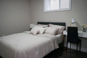 a bed with white sheets and a chair and a window at New Suite 15min from DT Van & Skytrain + Parking in Vancouver