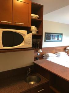 a kitchen with a microwave and a sink at Flat em Gramado in Gramado