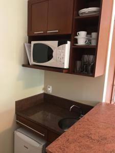 a microwave sitting on a shelf above a kitchen counter at Flat em Gramado in Gramado