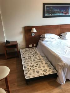 1 dormitorio con 1 cama y 1 mesa con lámpara en Flat em Gramado en Gramado