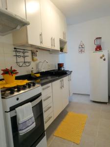 cocina con armarios blancos, fogones y nevera en Bate & Volta - Apartamentos com 2 quartos próximo ao SESC Bertioga, en Bertioga