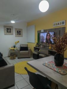 ein Wohnzimmer mit einem Sofa und einem TV in der Unterkunft Bate & Volta - Apartamentos com 2 quartos próximo ao SESC Bertioga in Bertioga