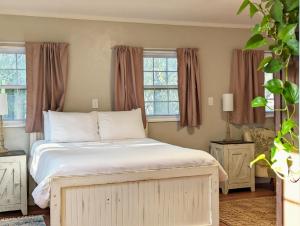 a bedroom with a bed with white sheets and windows at The Garden House of Downtown Manitou Springs in Manitou Springs