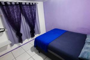 a bedroom with a blue bed and purple curtains at Casa dos Sonhos in Campo Grande