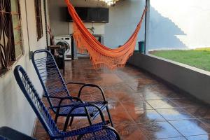 Duas cadeiras sentadas num alpendre com uma rede de descanso laranja em Casa dos Sonhos em Campo Grande