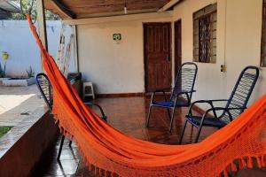 an orange hammock on a porch with two chairs at Casa dos Sonhos in Campo Grande