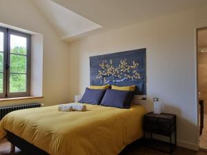 a bedroom with a large bed with yellow sheets and blue pillows at Luxe et tranquillité au vert: maison 6 chambres, piscine, proche du Mans, idéale familles et groupes - FR-1-410-361 in Parigné-lʼÉvêque