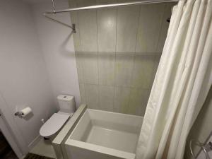La salle de bains est pourvue d'une baignoire, de toilettes et d'une douche. dans l'établissement New Apartment with 1 Bedroom - 1905, à Montréal