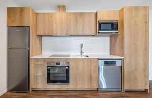 a kitchen with wooden cabinets and a stainless steel refrigerator at Central Park Residence in Auckland