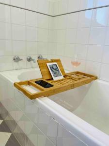 a tray with a clock and a glass of wine on a bath tub at Tide 'n' Seek: Family Beach House with Games Room in Vincentia