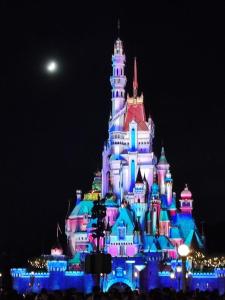 a disney castle is lit up at night at Relaince international guest house in Hong Kong