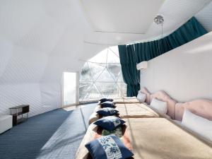 a row of beds in a room with a window at Fuji Hoshizorano Mura Tabist in Narusawa