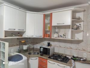 a kitchen with white cabinets and a sink and a microwave at Apartamento cobertura em balneário Camboriú in Balneário Camboriú