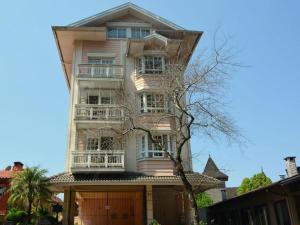 um edifício rosa alto com uma árvore em frente em LOCAR-IN GRAMADO - Duplex Solar da Borges em Gramado