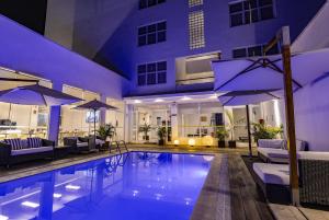 uma piscina com guarda-sóis e um hotel em Hotel Gran Palma Piura em Piura