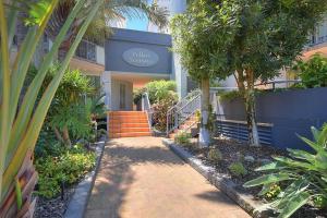 un bâtiment avec des palmiers et une passerelle devant dans l'établissement Beautiful 2 Bed Retreat 2 min walk to tramline, à Gold Coast