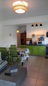 une cuisine avec des armoires vertes, une table et des chaises dans l'établissement La Kaz'ida, à Cilaos