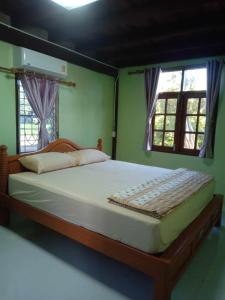 a large bed in a bedroom with two windows at The Orange House Thailand - Baan P'Nae Homestay in Ban Khlong Bang Khrok