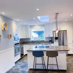 a kitchen with white cabinets and a island with two bar stools at Quiet Three Bedrooms House in Victoria