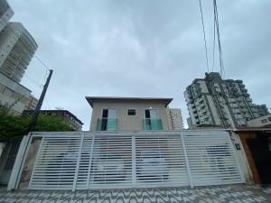 um edifício atrás de uma cerca em frente a alguns edifícios em Casa de Praia - Distância de 100 metros na Praia Grande