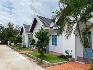 a white house with a black roof and a palm tree at B2 Hotel Savannakhet in Savannakhet