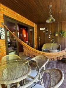 a patio with wicker chairs and a glass table at Casa de campo com cachoeira no quintal in Gaspar