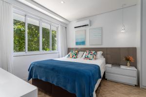 um quarto com uma cama com lençóis azuis e janelas em Fantastic sea view - Maison Ipanema Prime no Rio de Janeiro