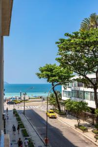 a city street with a beach and a yellow taxi at Fantastic sea view - Maison Ipanema Prime in Rio de Janeiro