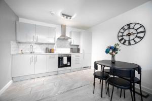 a kitchen with a table and a clock on the wall at A Stylish One-Bedroom Next to London Museum! in Colindale