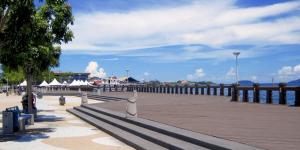 a boardwalk with a pier with white umbrellas on it at Likas Square Cozy Family 3 bedrooms - Keysuites in Kota Kinabalu