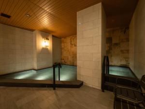 a swimming pool in a building with a tile wall at Loisir Hotel Kyoto Toji in Kyoto