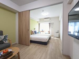 ESLEAD HOTEL Namba South Ⅲ في أوساكا: غرفه فندقيه بسرير واريكه