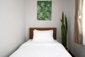 a bedroom with a bed with white sheets and a plant at Homie Non - โฮมมี่ นนท์ in Ban Bang Khwang