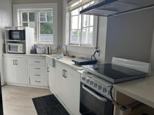 La cuisine est équipée de placards blancs et d'un four avec plaques de cuisson. dans l'établissement Mt Eden Tidy Bedroom rm7, à Auckland