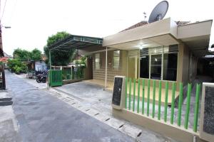 ein kleines Haus mit einem grünen Zaun an einer Straße in der Unterkunft Athala homestay syariah in Yogyakarta