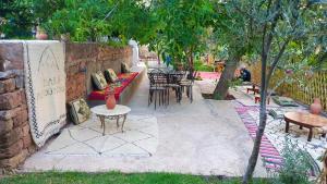 a patio with tables and chairs and tables and trees at Dar assounfou in Demnat