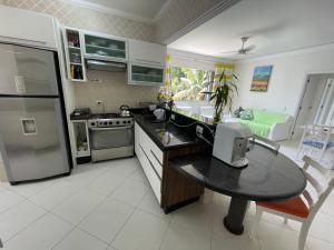 a kitchen with a refrigerator and a table in it at Apartamento Maré Mansa a 30 metros da praia Mansa em Caiobá com Wifi in Caiobá