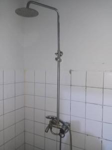 a shower in a bathroom with white tiles at PagersHome Suites- RUSTIC in Kigali