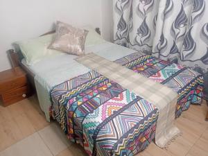 a bed with a comforter and pillows on it at PagersHome Suites- RUSTIC in Kigali