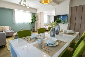 a dining room with a white table and green chairs at Premium Apartment Hotel Tokyo East in Tokyo