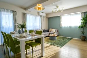 sala de estar con mesa blanca y sillas verdes en Premium Apartment Hotel Tokyo East, en Tokio