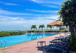 a swimming pool with chairs and an umbrella and the ocean at Holiday Inn Melaka, an IHG Hotel in Malacca