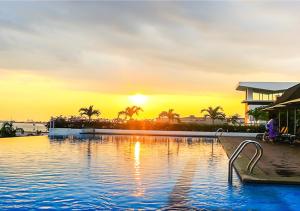 a swimming pool with a sunset in the background at Holiday Inn Melaka by IHG in Malacca