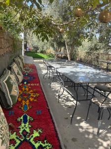 a table and chairs with a colorful rug on a sidewalk at Dar assounfou in Demnat