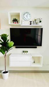 a white entertainment center with a tv and a plant at MM’s Place at Woodhills Tagaytay in Tagaytay