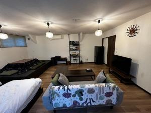 ein Wohnzimmer mit einem Sofa und einem TV in der Unterkunft ツナゲル青森安方Villa Suite in Aomori