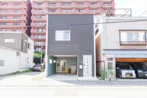 ツナゲル青森安方Villa Suite في أوموري: منزل أسود مع مرآب أمام مبنى