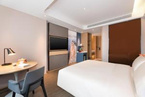 um quarto de hotel com uma cama branca, uma secretária e uma cadeira em Atour Hotel Xian Bell Tower Yongningli em Xi'an