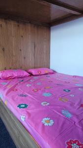 a bed with a pink blanket with flowers on it at Tea corner Guest house in Darjeeling